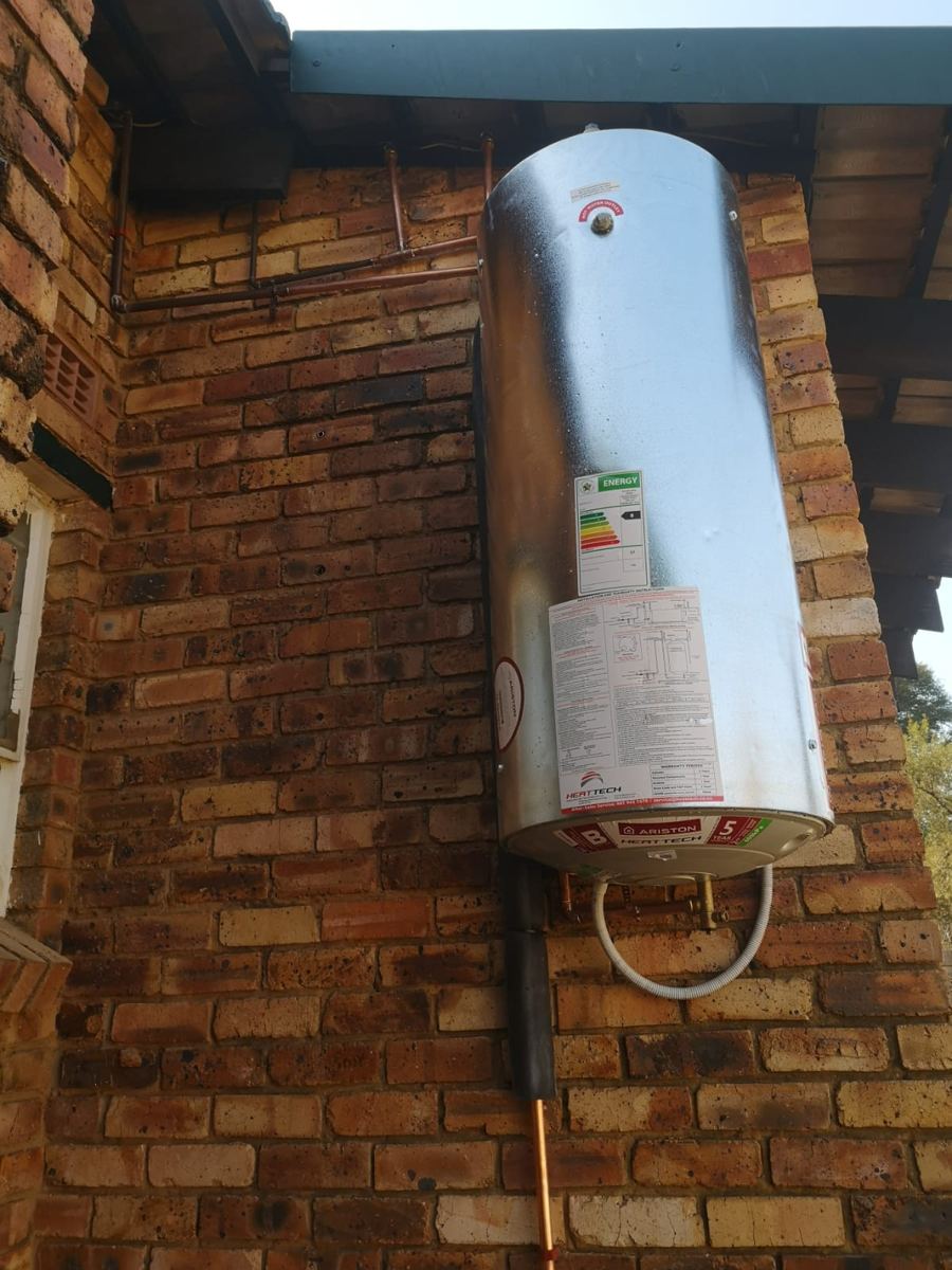 New Ariston vertical geyser installed under the eave of a brick house with copper pipework