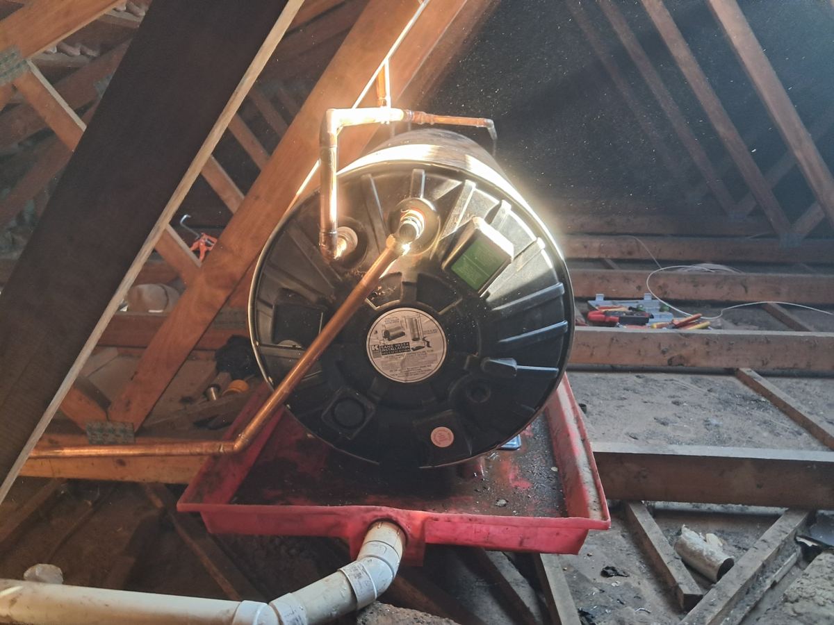Geyser in a red drip tray with a PVC overflow drain and copper pipework