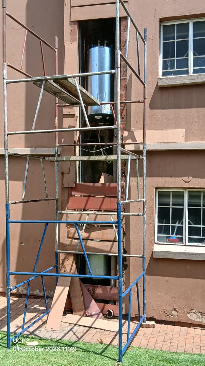 Scaffold set up against a building to replace a geyser in a second-floor duct